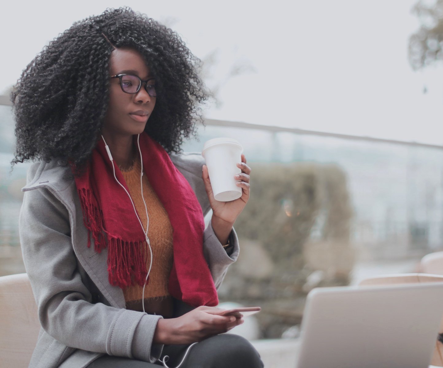 Female student drinking coffee and looking at laptop